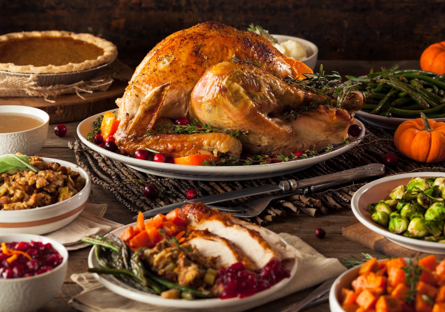 Photo of Thanksgiving Dinner with giant turkey in the center surrounded by side dishes