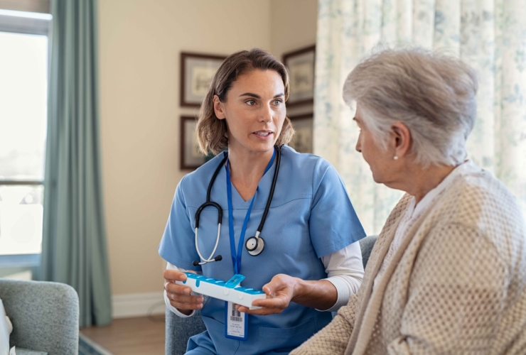 A young nurse, specializing in Alzheimer's home care services, patiently explains the dosage of medicine to an elderly patient.