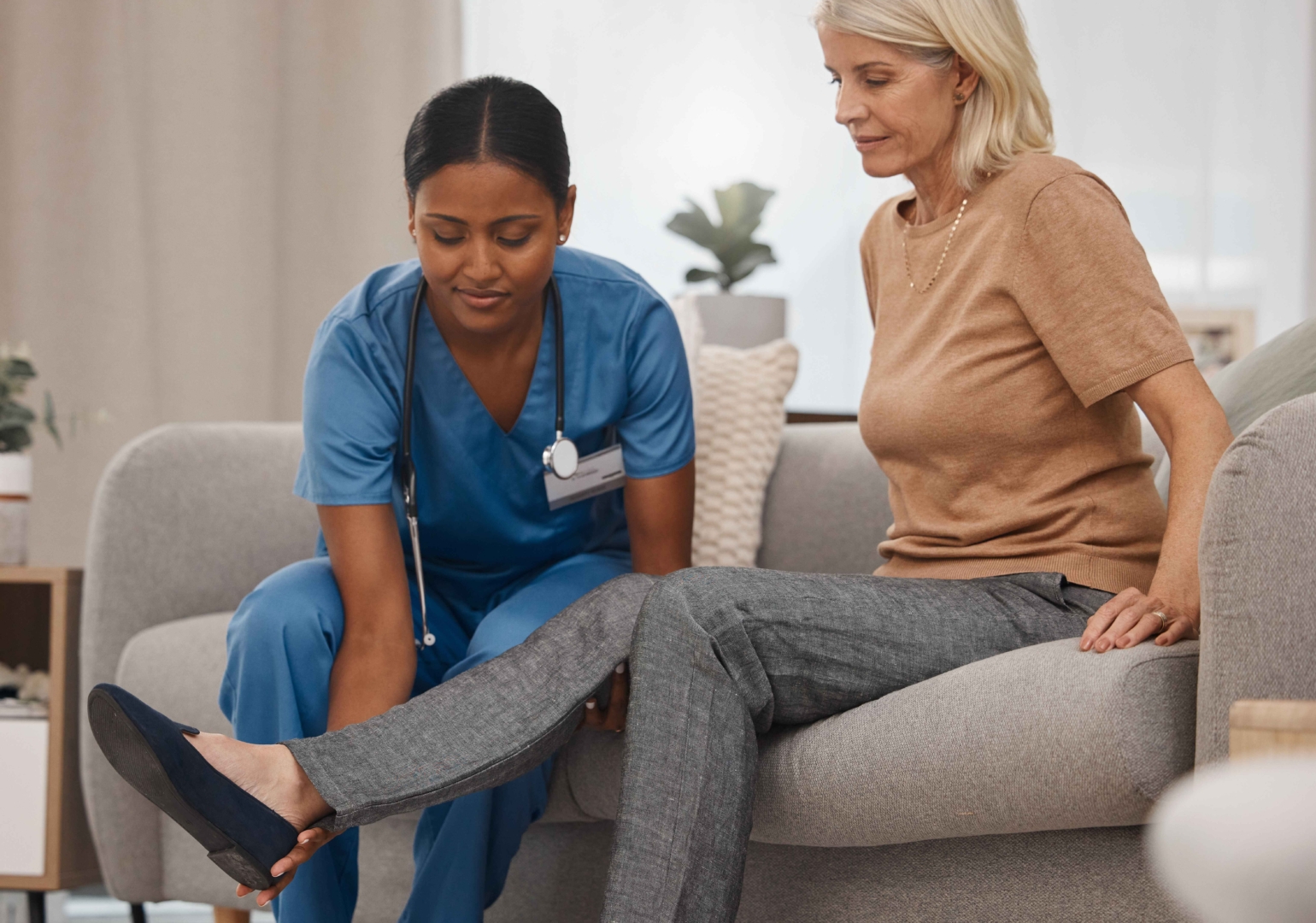 Foot, nurse or senior woman with physical therapy for injury, rehabilitation massage and healthcare worker help with pain. Elderly patient, doctor and physio therapist or medical expert on sofa.
