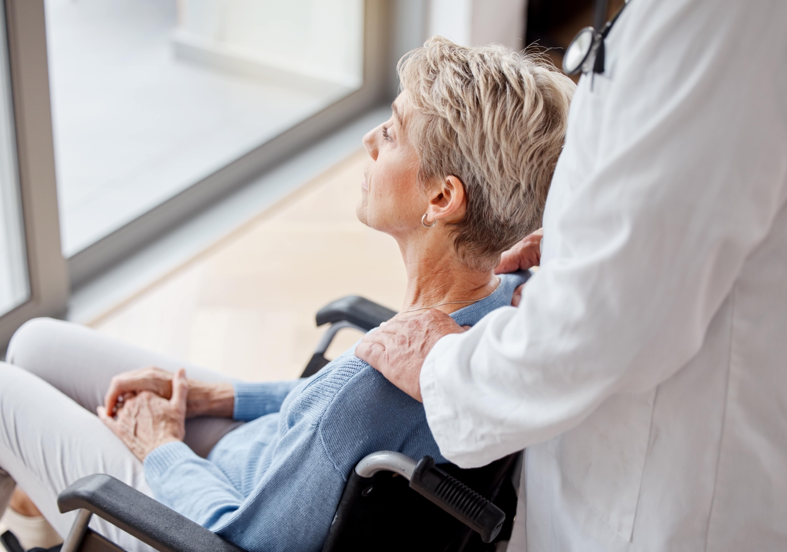Senior woman, wheelchair and window with nurse, home care and support for healthcare, rehabilitation or relax.